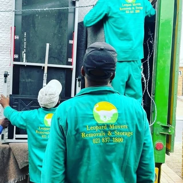 Movers in teal uniforms loading a large item into a moving truck; Leopard Movers Removals & Storage logo on back of shirt.